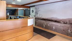 A reception desk with a view of sailboats on a body of water. - Hotel San Glorio (Santander)
