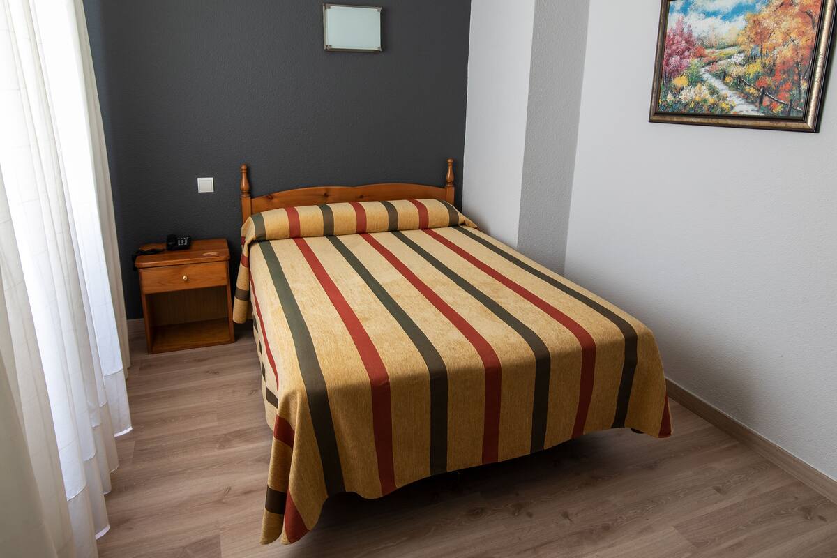 Un dormitorio con cama, mesita de noche y un cuadro en la pared.