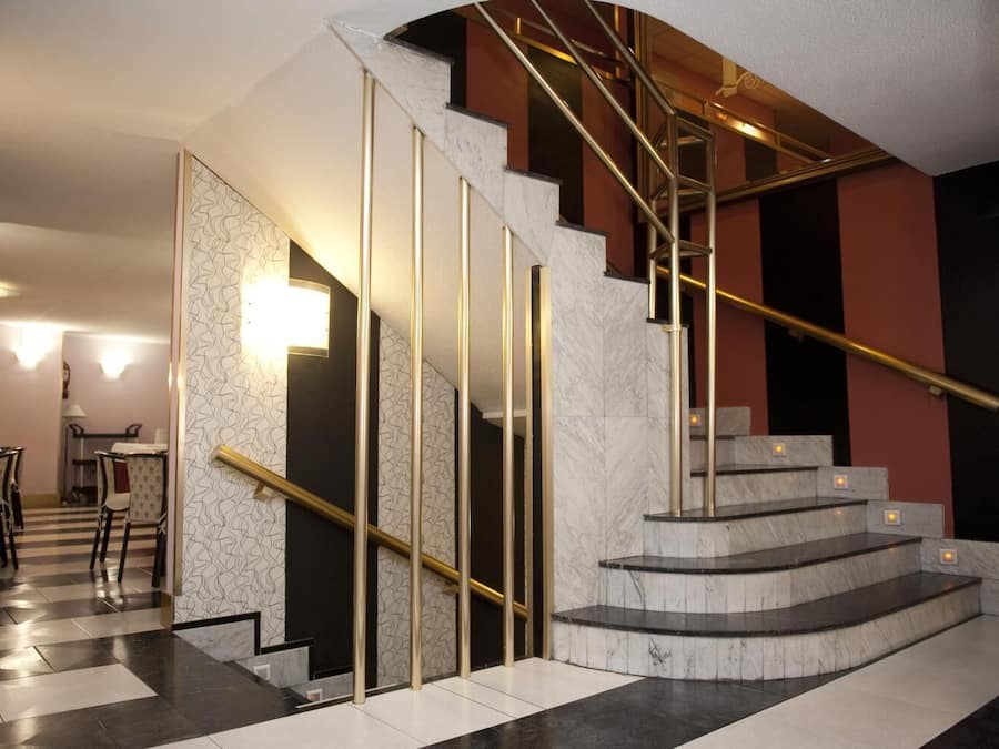 A modern interior with a marble staircase, a dining area with chairs, and a patterned wall.
