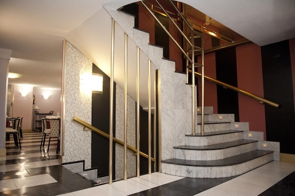 Un interior moderno con una escalera de mármol, un comedor con sillas y un muro estampado.