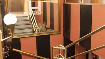 Eine Treppe mit schwarzen und orangefarbenen Wänden, einem Geländer und einem Spiegel, der das Innere widerspiegelt.