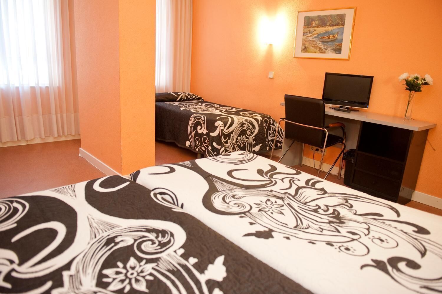 Habitació d'hotel amb dos llits, un escriptori amb televisió i un quadre al mur.
