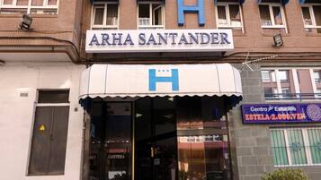 Un edificio con un letrero que dice "ARHA SANTANDER" y una gran 'H' azul en el toldo.