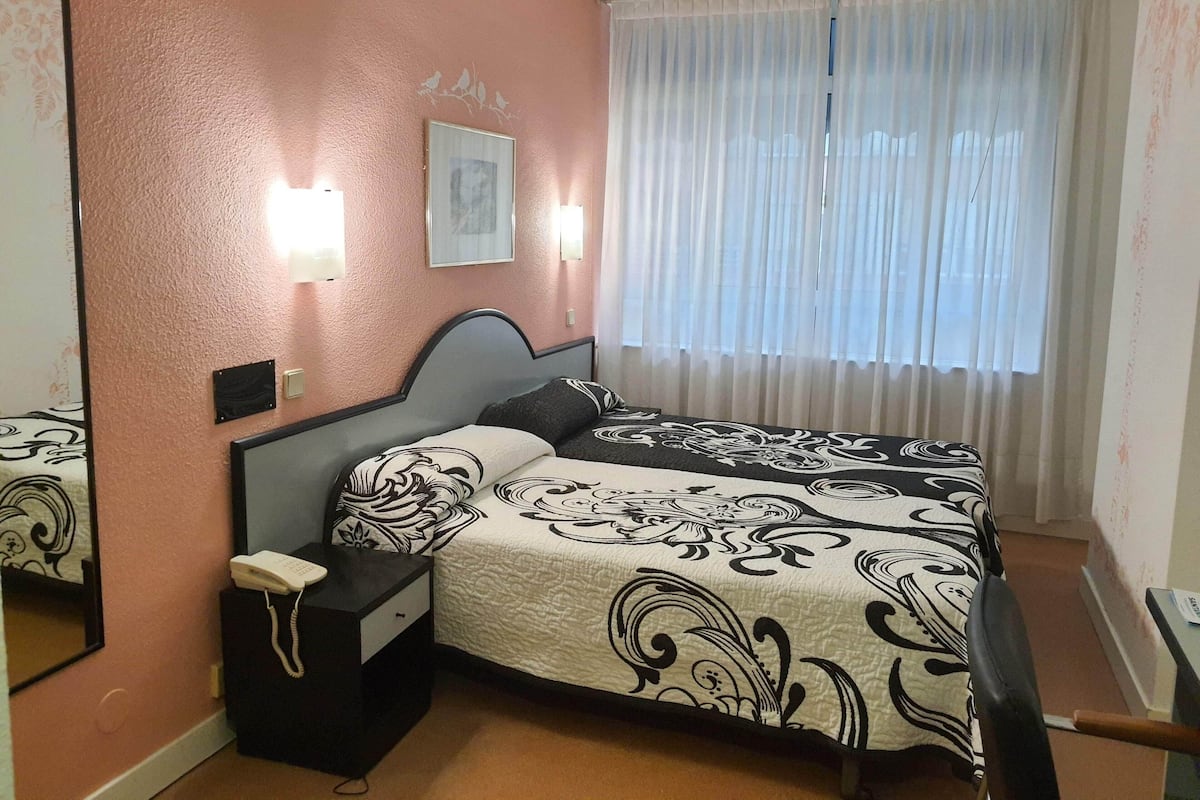 A bedroom with a bed, bedside table, and a telephone.
