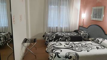 Habitación de hotel con dos camas, una silla, un ventanal con cortinas y un cuadro colgado en la pared.