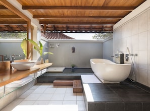 Ein modernes Badezimmer mit freistehender Badewanne, einem großen Spiegel und einer Holzauskleidung mit Waschbecken.