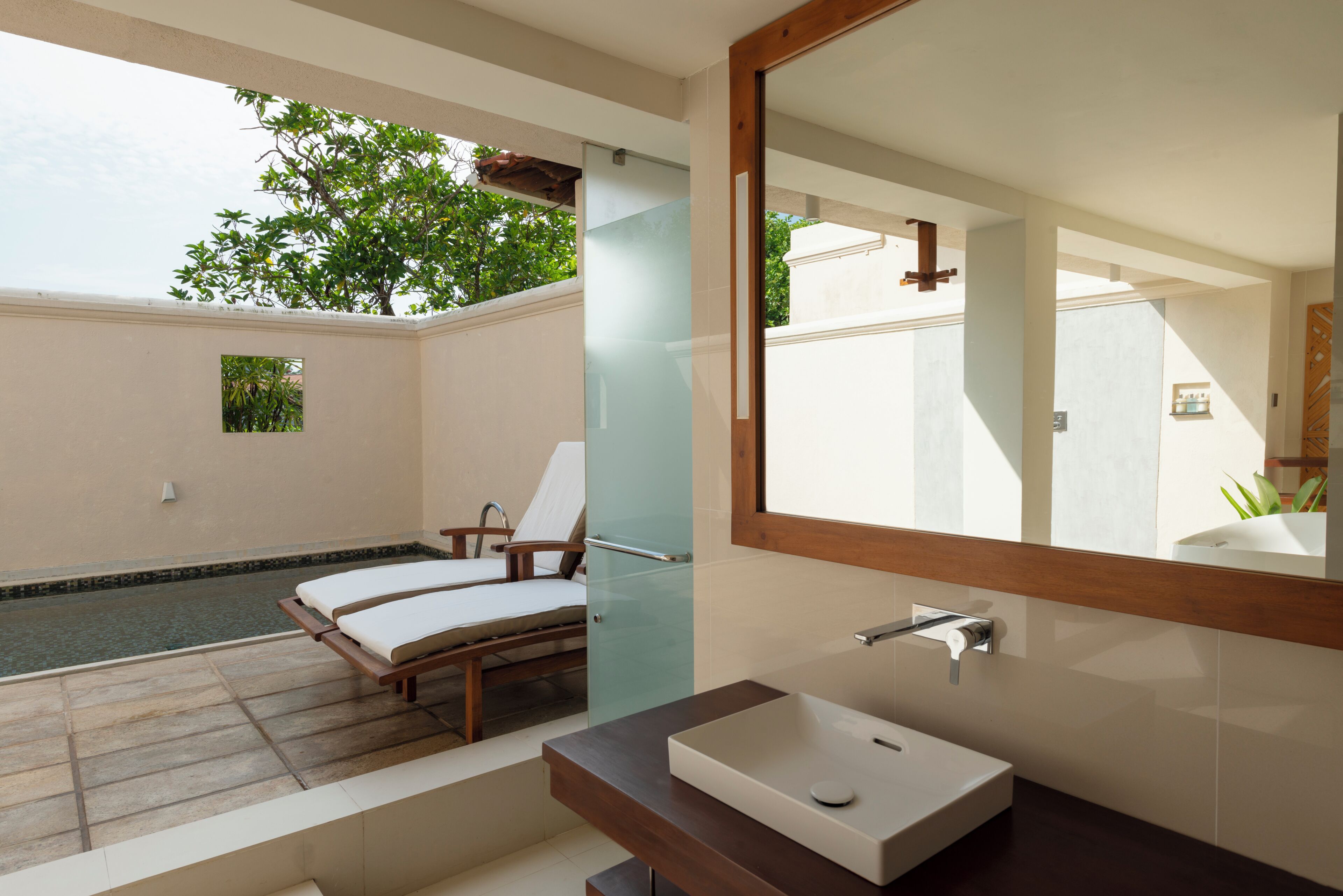 A modern bathroom with a large mirror, a rectangular sink, and a glass-enclosed shower area.
