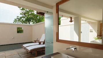 A modern bathroom with a large mirror, a rectangular sink, and a glass-enclosed shower area.