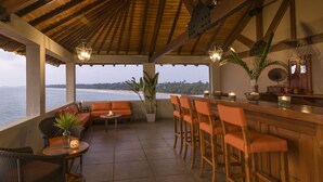 Un área de estar al aire libre cubierta con vista al océano, mobiliario de madera y un bar.