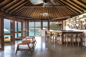 A spacious room with a wooden ceiling, a bar area with stools, and a view of the ocean. - Jetwing Saman Villas, A Luxury Reserve - Adults Only (Induruwa)