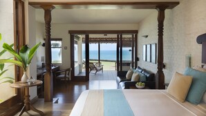 Un dormitorio con una cama grande, vistas al océano, un comedor y una zona de estar también con vistas.
