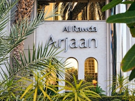 The exterior of Al Rawda Arjaan with a signboard, surrounded by greenery.