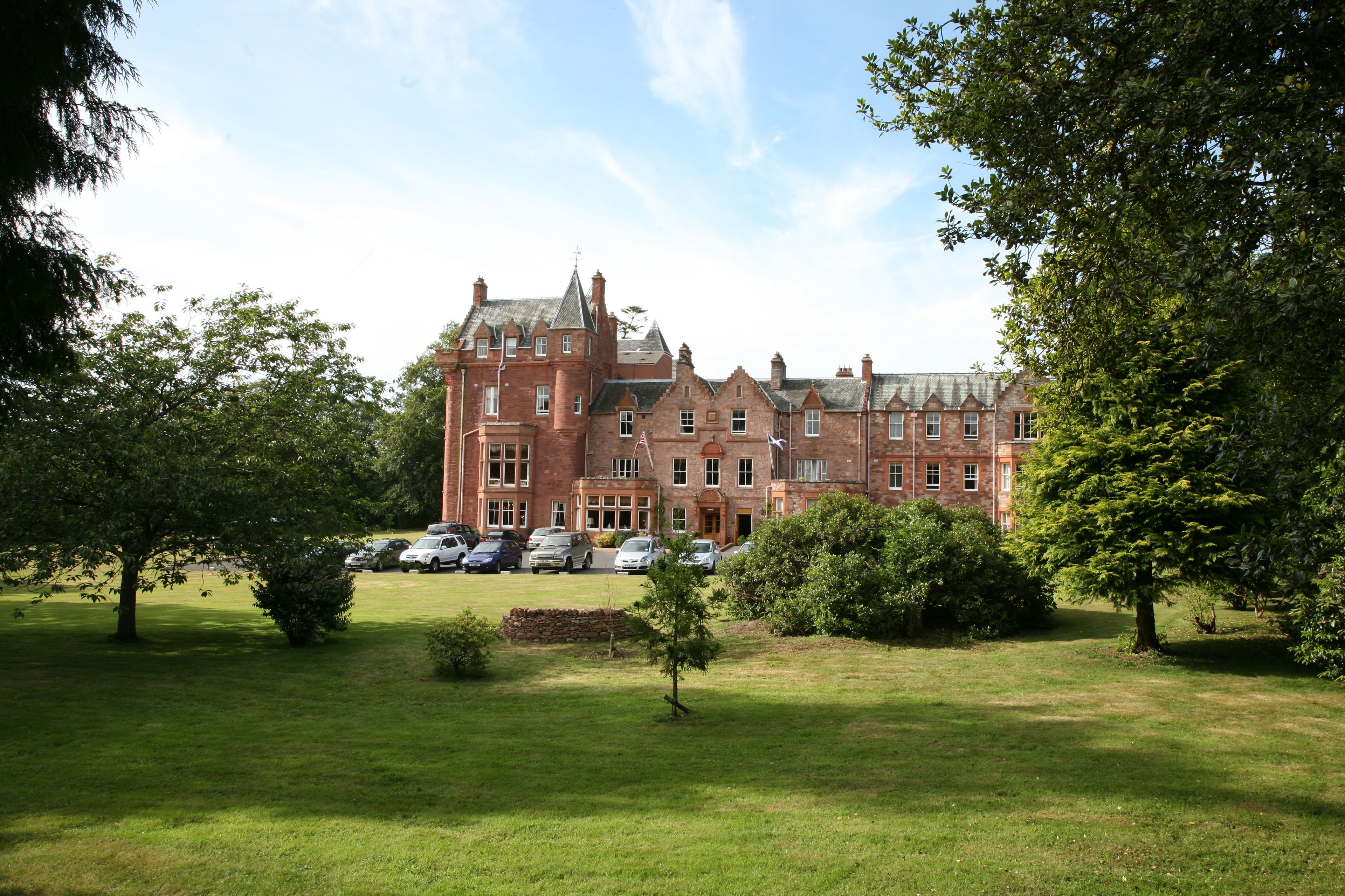 A large, historic brick building with multiple windows and a well-maintained lawn in front.