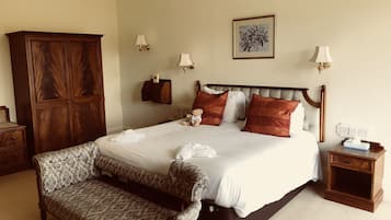 A neatly arranged bedroom with a large bed, a wooden wardrobe, a bedside table, and a bench.
