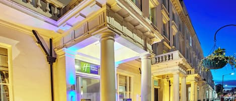 A hotel entrance with a covered porch, columns, and a Holiday Inn Express sign.