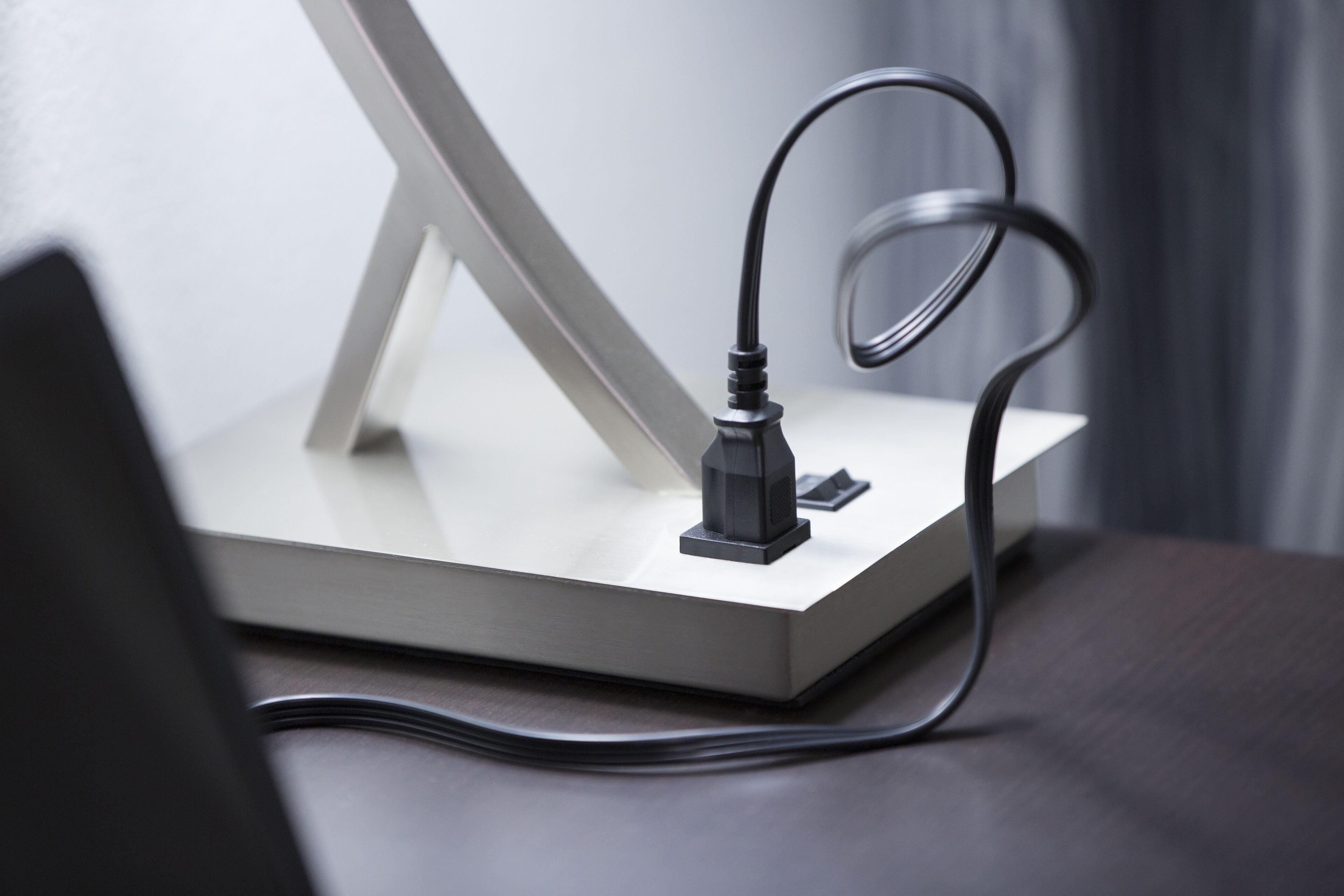 A modern desk setup with a laptop, a monitor, and a charging cable.