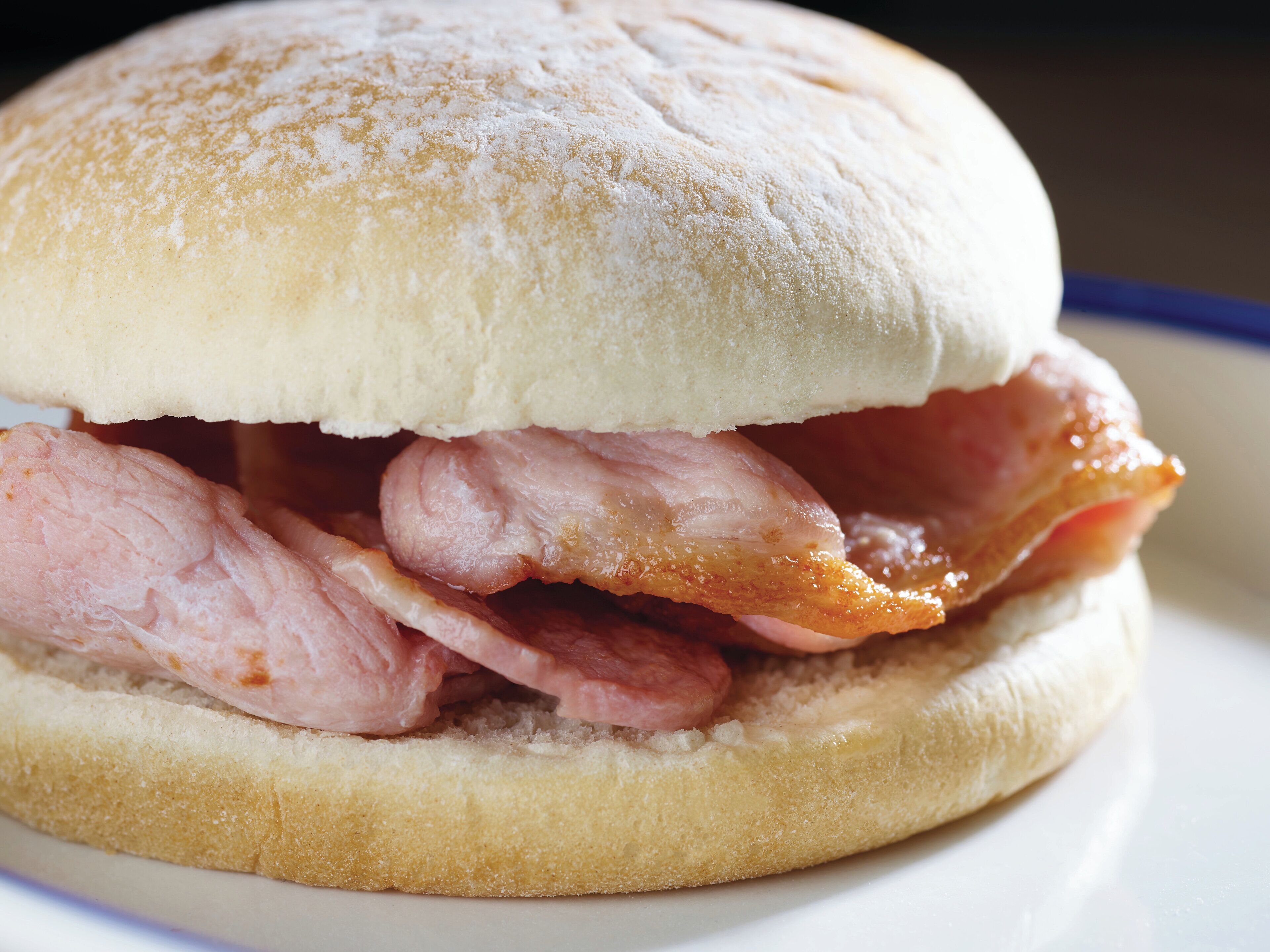 A sandwich with a bun, bacon, and a slice of cheese.