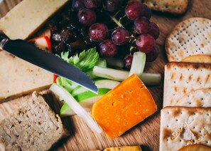 Eine Auswahl an Käse, Crackern und Trauben auf einer Holzplatte.