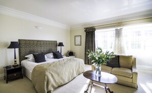 Ein Hotelzimmer mit einem großen Bett, zwei Nachttischen mit Lampen, einem Sofa und einem kleinen Tisch mit Blumen.