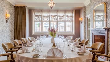 Une salle à manger élégante, avec une table ronde dressée pour le repas, entourée de chaises rembourrées.
