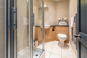 Ein modernes Badezimmer mit Duschkabine aus Glas, einem Waschbecken, einer Toilette und Holzschränken.