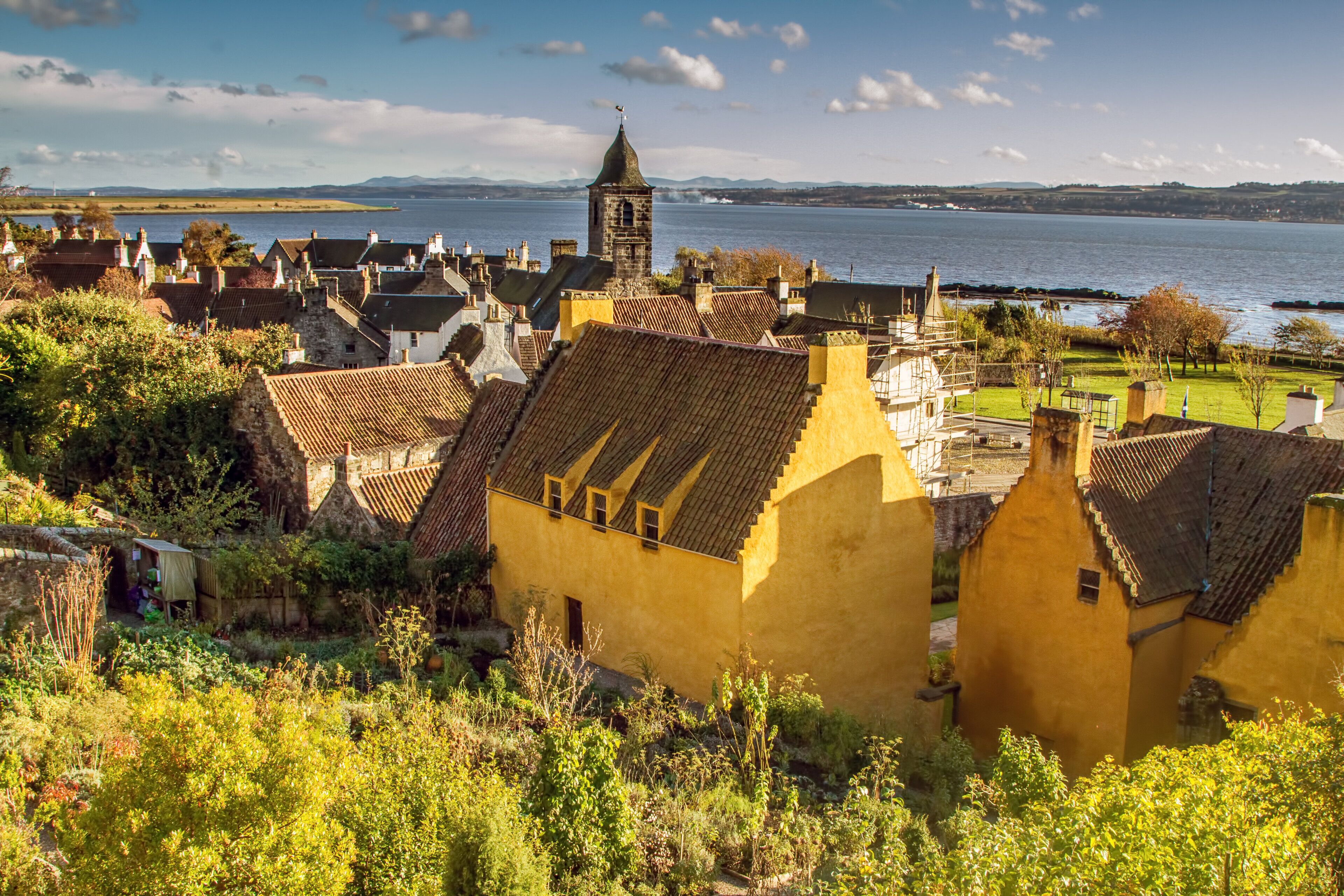 A coastal town with traditional architecture, a prominent tower, and a view of the sea.