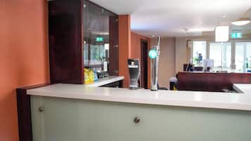 A hotel reception area with a counter, a glass display case, and a Guinness branded refrigerator.