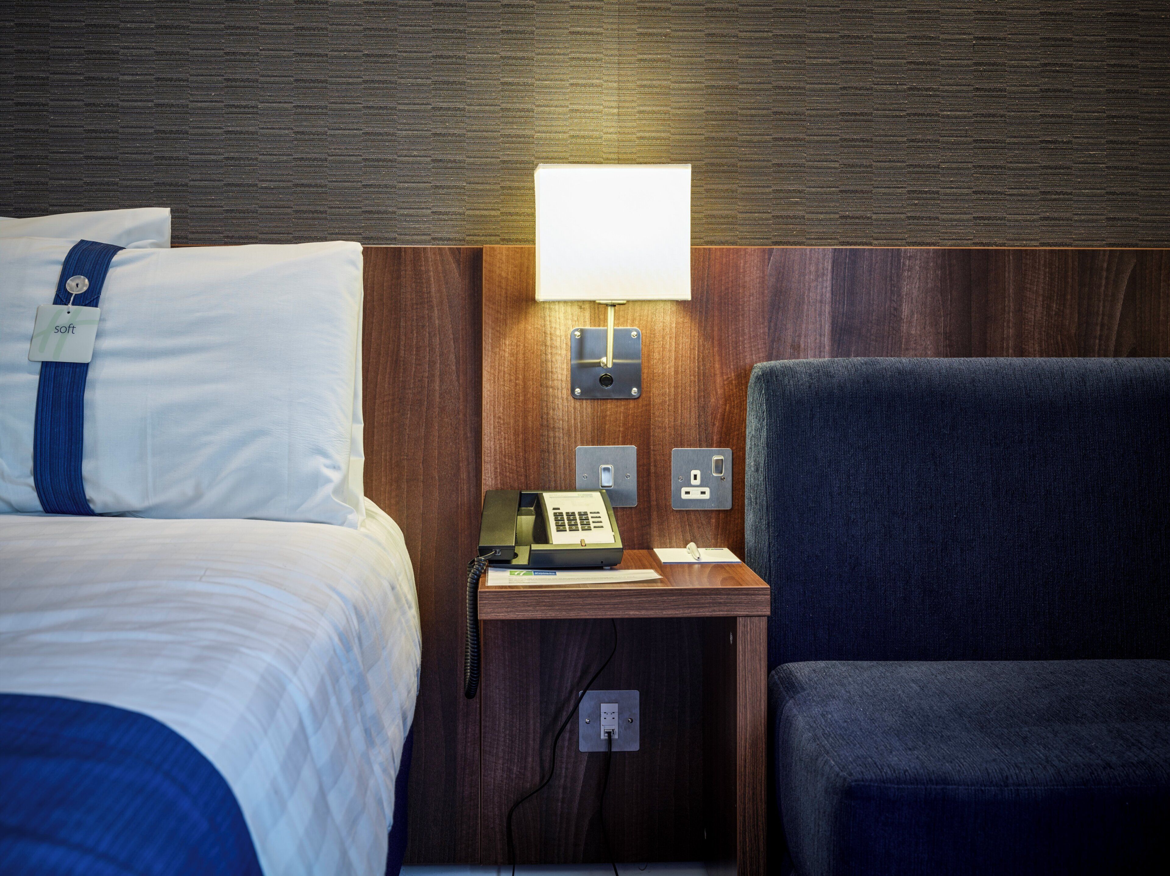 Ein Hotelzimmer mit einem Bett, einem Schreibtisch mit Telefon und einem Sessel.