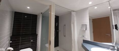 A modern bathroom with a toilet, a shower, and a sink.