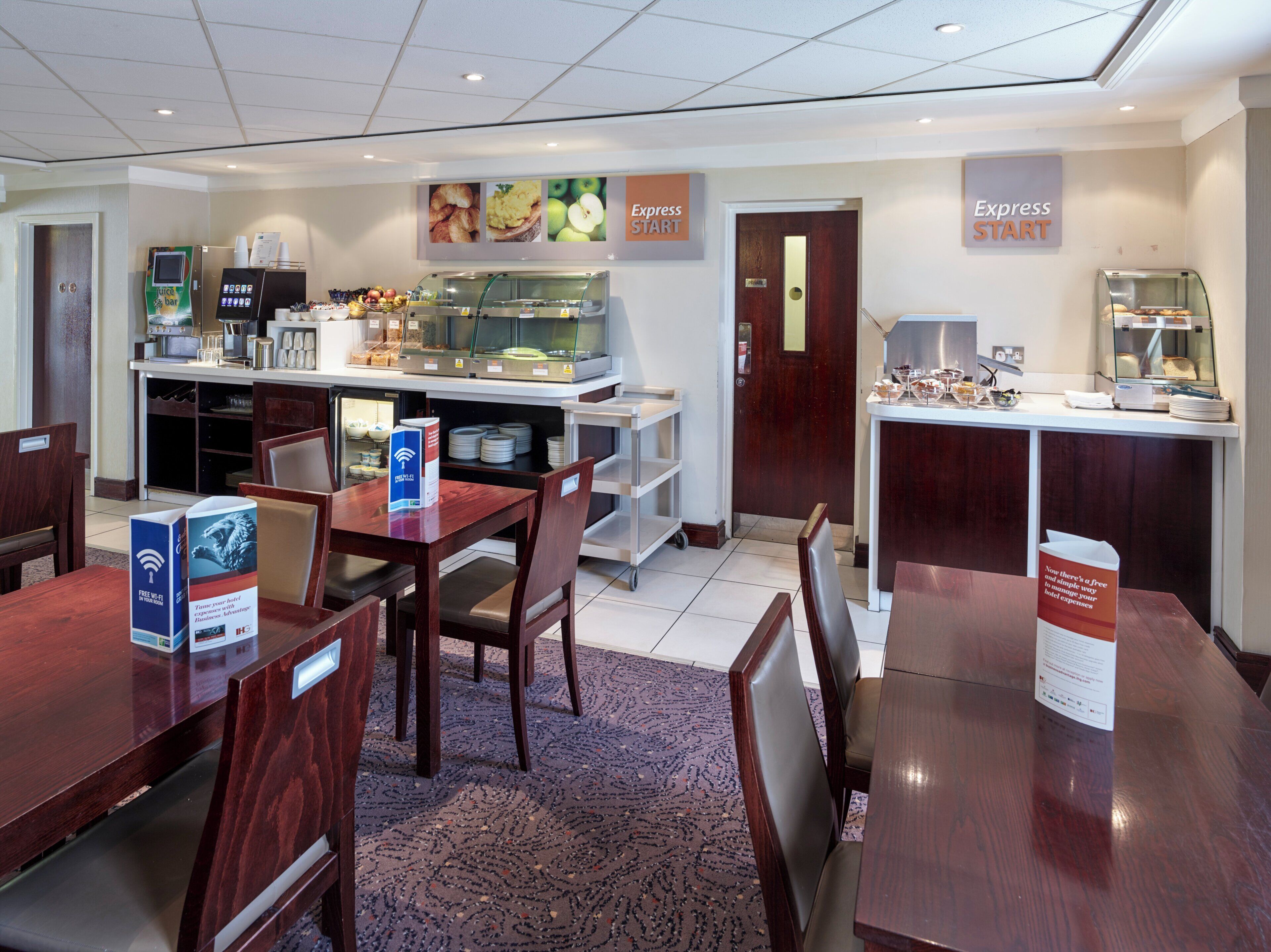 Een hotelkamer met een ontspanningsruimte, inclusief een buffet, een koffieapparaat en een bordje met de tekst 'Express START'.