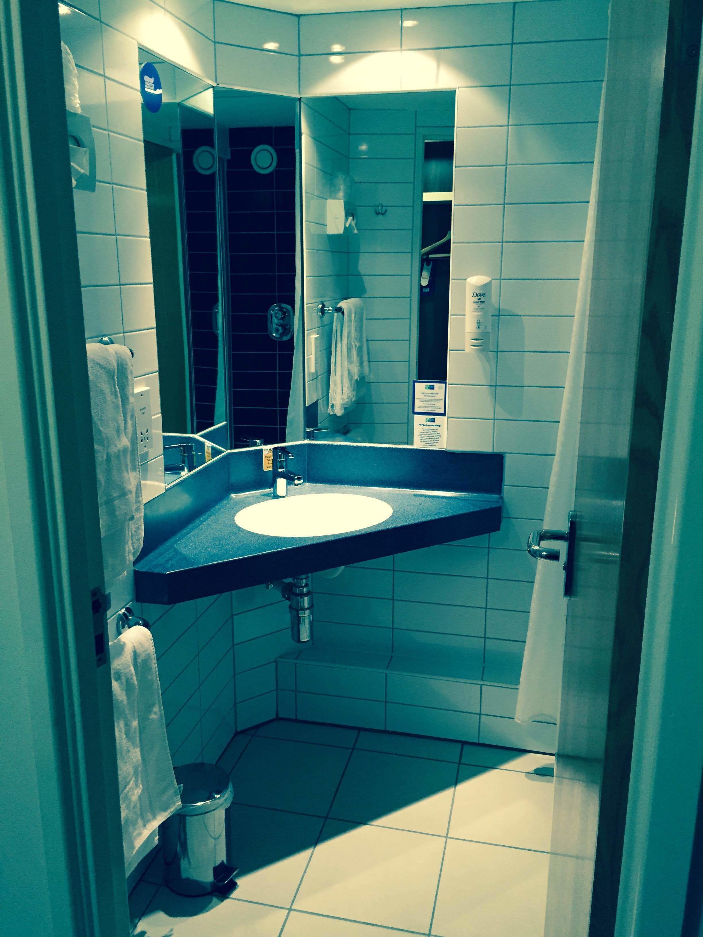 A bathroom with a sink, mirror, towel rack, and shower area.