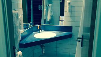 Un baño con lavamanos, espejo, toallero y zona de ducha.