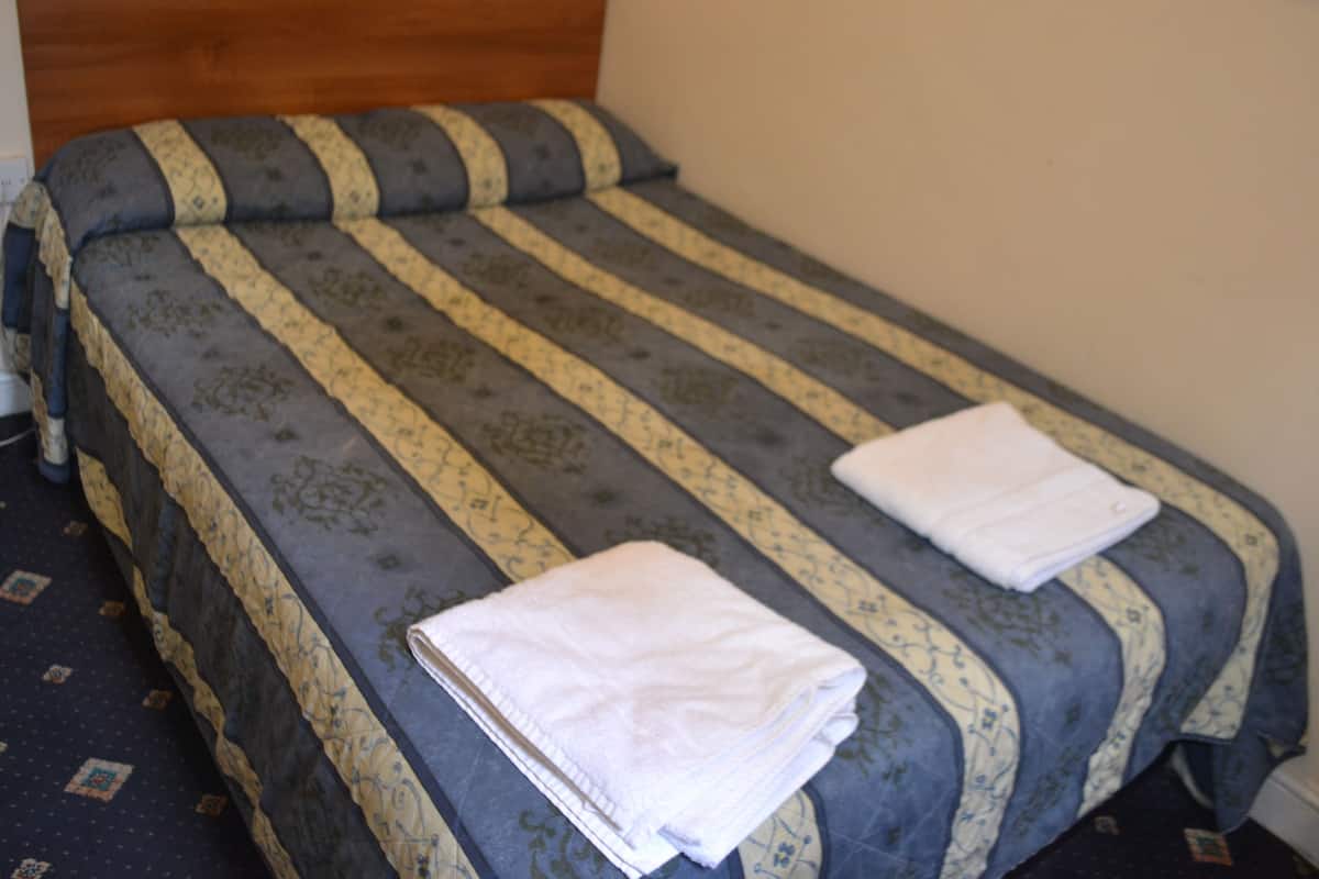 A single bed with a striped bedspread and two neatly folded white towels.