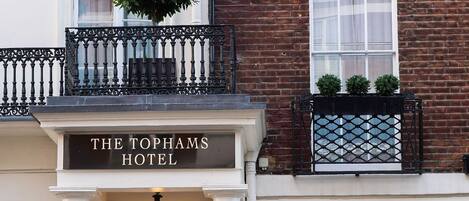 The Tophams Hotel with a classic facade, a dark entrance door, and a sign above the door.
