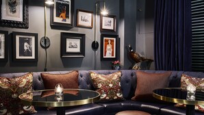 A modern lounge area with a dark blue sofa, round tables, and framed artwork on the wall. - Tophams Hotel (London)