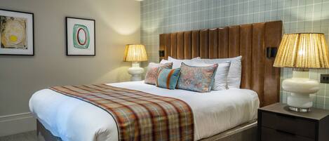 A neatly made bed with a plaid blanket, two bedside lamps, and a nightstand with a lamp.