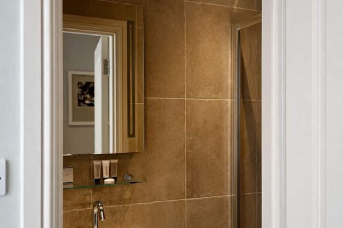 Ein Badezimmer mit Spiegel, Waschbecken und Duschbereich.