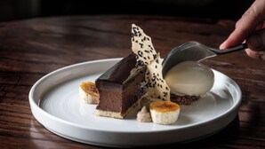 A dessert plate with a chocolate cake, banana slices, and a scoop of ice cream.