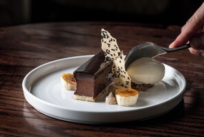 A dessert plate with a chocolate cake, banana slices, and a scoop of ice cream.
