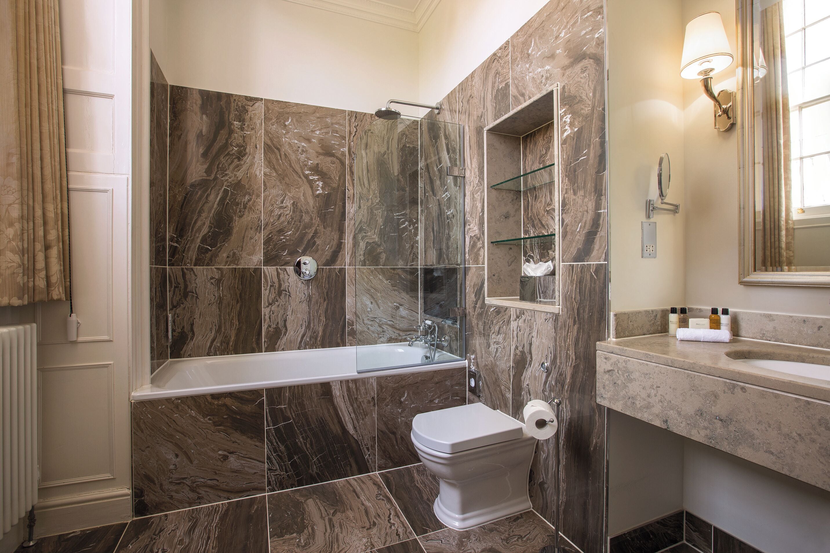 A bathroom with a bathtub, toilet, and a glass-enclosed shower area.