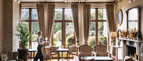 A spacious room with a large window, a chandelier, and a fireplace.