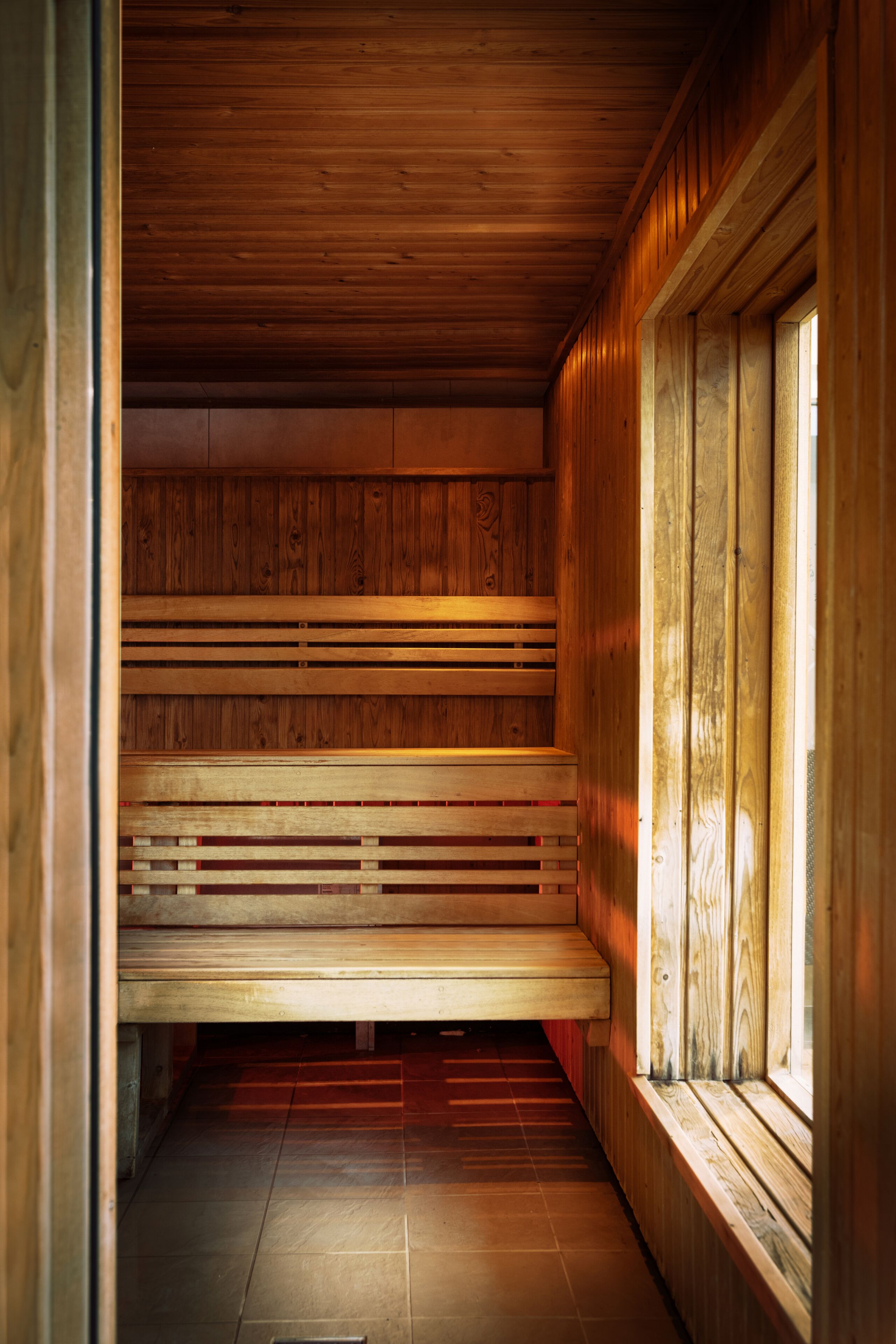 A wooden sauna with benches and a tiled floor.
