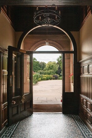 An arched doorway leading to a courtyard with a tiled floor and a view of greenery. - Rookery Hall Hotel (Nantwich)