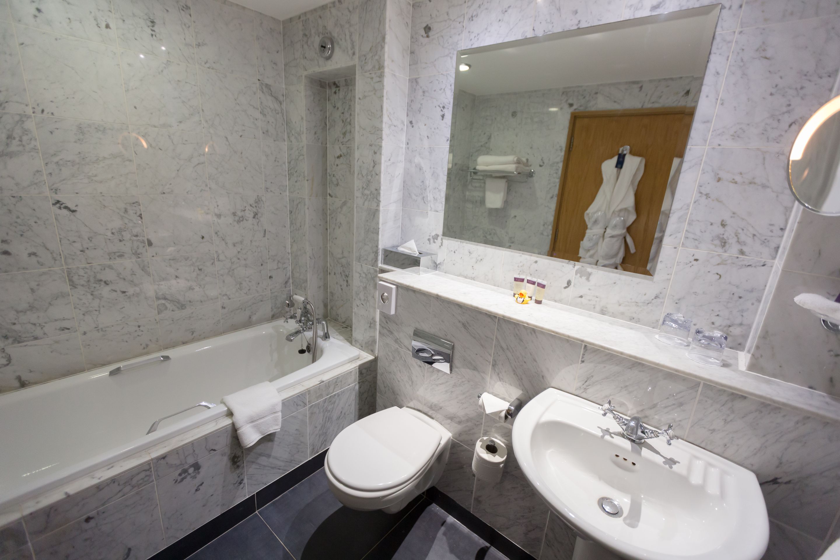 A bathroom with a bathtub, toilet, and sink, all with marble tiles.