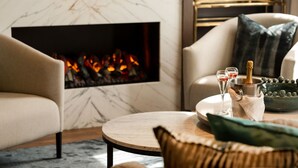 A cozy living room with a fireplace, a round coffee table, and a seating area with a sofa and armchairs. - Europa Hotel (Belfast)