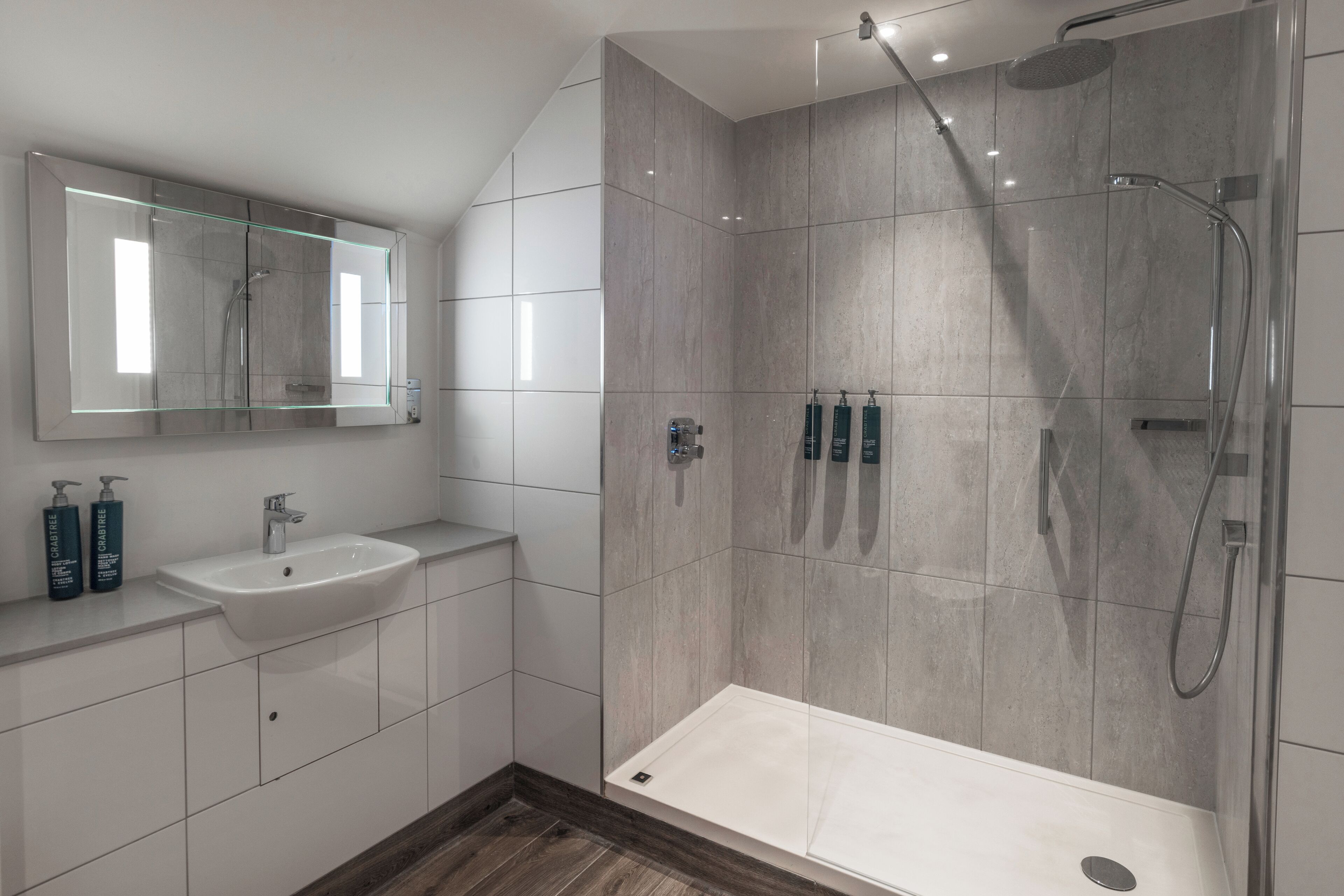 Une salle de bain moderne avec une douche à parois de verre, un lavabo avec un miroir et des articles de toilette posés sur le comptoir.