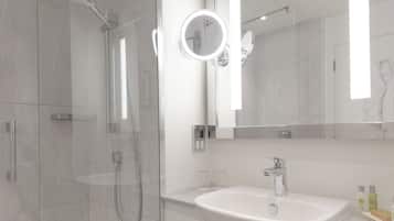 A modern bathroom with a glass-enclosed shower, a white sink, and a large mirror with a round light.