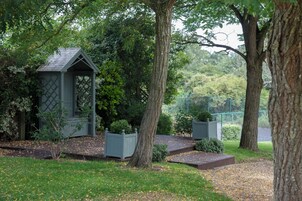 Un jardín exuberante con árboles, un sendero y un quiosco.