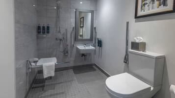 Ein modernes Badezimmer mit Dusche, Toilette, Waschbecken und einem gerahmten Bild an der Wand.