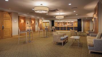 A hotel lobby with a bar area, seating arrangements, and a patterned carpet.
